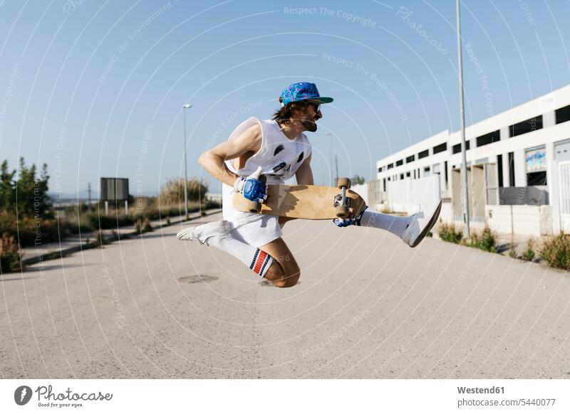 Sportlicher Mann springt mit Skateboard auf Händen über den Boden halten sportlich Männer männlich Trick Skateboarden Skateboardfahren Skateboarding