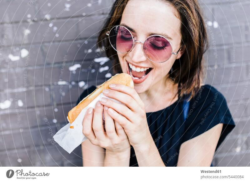 Porträt einer Frau, die einen Hot Dog isst weiblich Frauen Hot Dogs essen essend Erwachsener erwachsen Mensch Menschen Leute People Personen abbeißen abbeissen