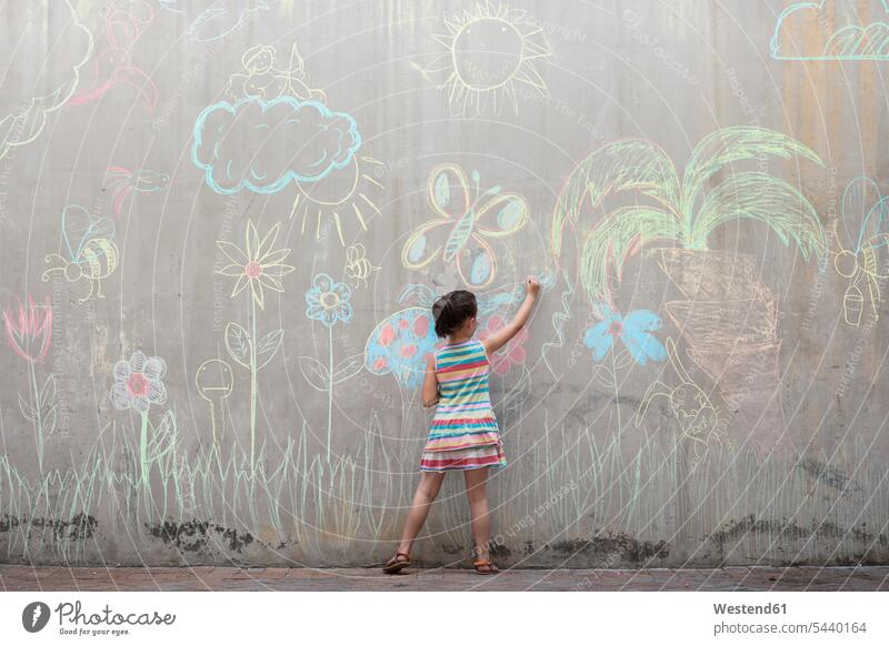 Mädchen zeichnet bunte Bilder mit Kreide auf eine Betonwand zeichnen Zeichnung weiblich farbig mehrfarbig Betonwände Betonwaende Kind Kinder Kids Mensch