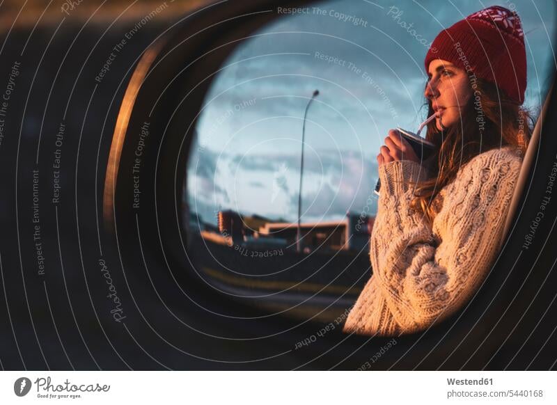 Island, junge Frau mit Kaffee zum Mitnehmen bei Sonnenuntergang, im Außenspiegel gespiegelt unterwegs auf Achse in Bewegung Rückspiegel Seitenspiegel
