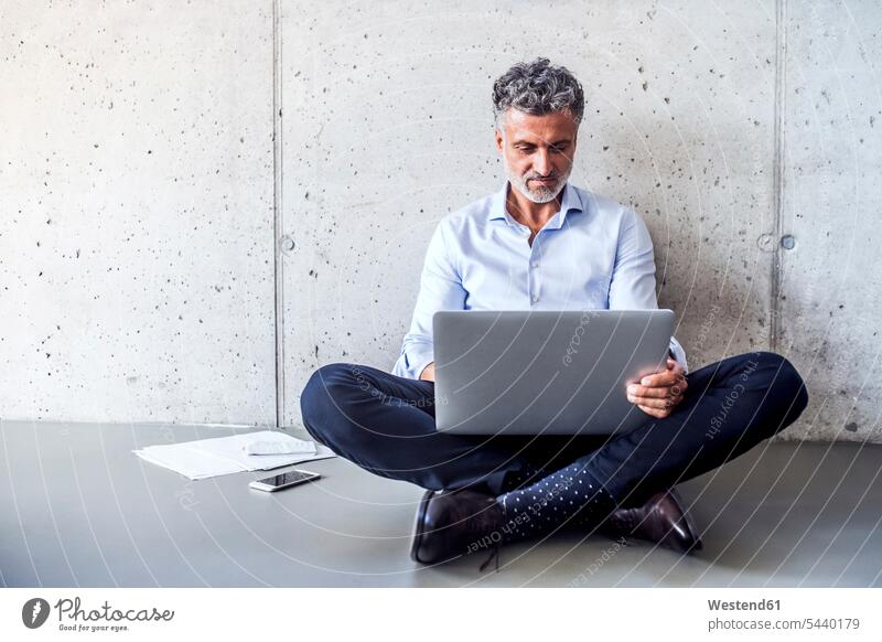 Ein reifer Geschäftsmann sitzt auf dem Boden und benutzt einen Laptop Businessmann Businessmänner Geschäftsmänner Böden Boeden sitzen sitzend Notebook Laptops