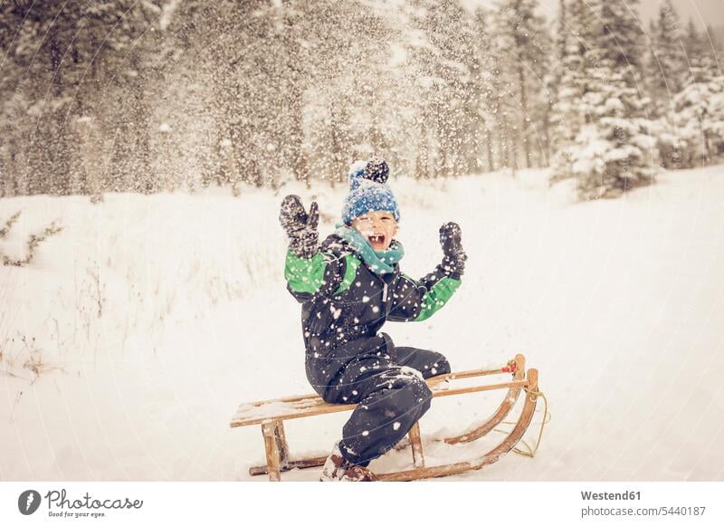 Deutschland, Bayern, Berchtesgadener Land, glücklicher Junge auf dem Schlitten Europäer Kaukasier kaukasisch Europäisch kalt Kälte Kaelte schneien Schneefall