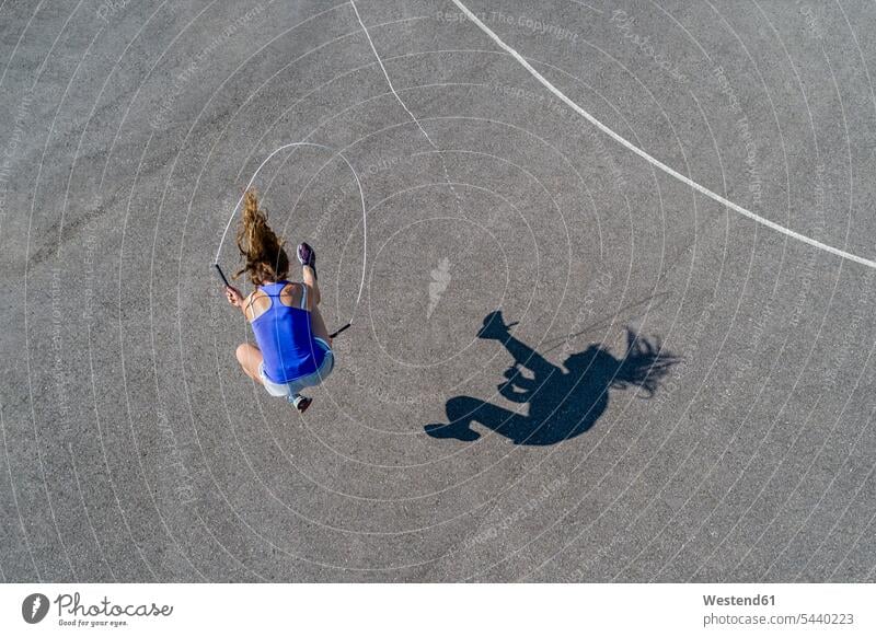 Luftaufnahme einer jungen Frau beim Seilspringen, Schatten sportlich trainieren Sportlerin Sportlerinnen Springseil Springseile Sprungseile seilspringen