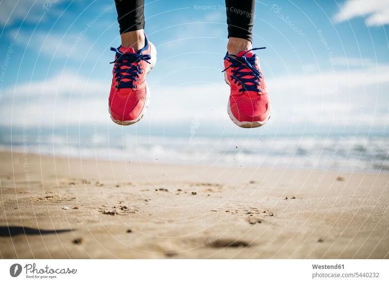 Füße einer Frau, die am Strand springt Turnschuhe Fitness fit Gesundheit gesund Aktivität Aktivitaet aktiv Vitalität Vitalitaet Elan Schwung dynamisch Energie