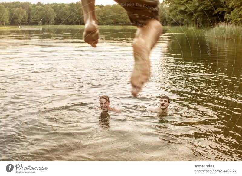 Junger Mann springt in Steinbruch-Teich Rückansicht Rückenansicht von hinten Rueckansicht Rueckenansicht Baggersee Wasseroberfläche Wasseroberflaeche