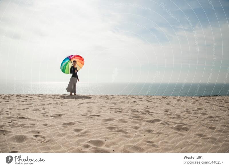 Frau mit bunten Regenschirm zu Fuß am Strand farbig mehrfarbig Strandspaziergang weiblich Frauen Beach Straende Strände Beaches Freiheit frei gehen gehend geht