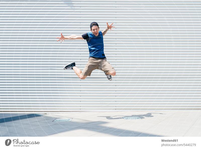 Junger Mann springt in die Luft springen hüpfen Männer männlich Sprung Spruenge Sprünge Erwachsener erwachsen Mensch Menschen Leute People Personen Luftsprung