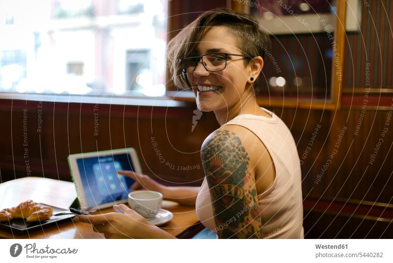 Porträt einer tätowierten jungen Frau, die mit einem digitalen Tablett in einem Café sitzt Gijon Top Tops Drahtlose Technologie drahtlose Verbindung
