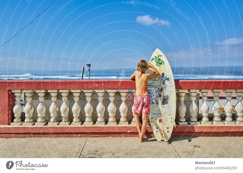 Chile, Pichilemu, Junge an Uferpromenade stehend mit Surfbrett Surfbretter surfboard surfboards Buben Knabe Jungen Knaben männlich Uferpromenaden steht Meer