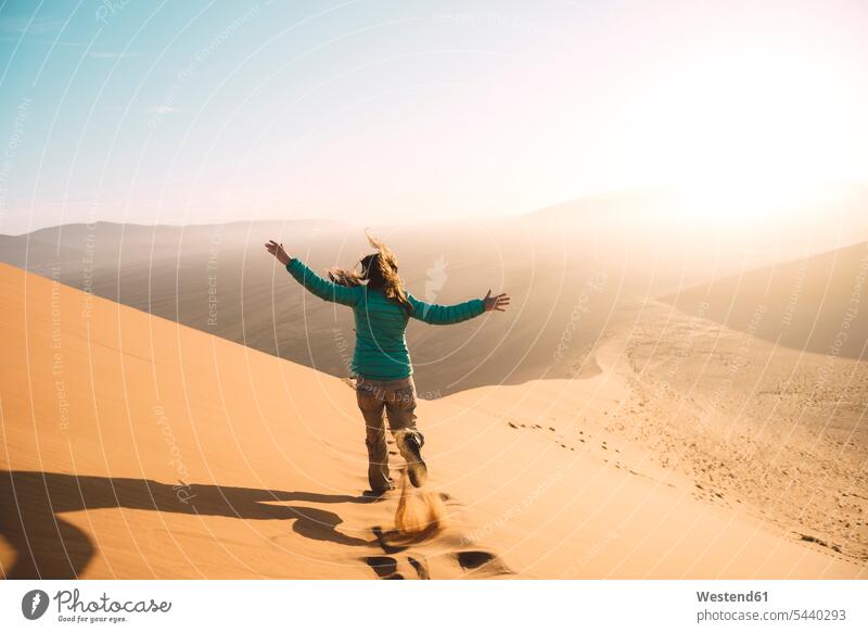 Namibia, Namib-Wüste, Sossusvlei, Frau rennt bei Sonnenaufgang die Düne 45 hinunter Europäer Kaukasier Europäisch kaukasisch Natur Wüsten Außenaufnahme draußen