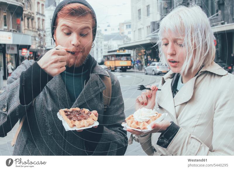 Belgien, Antwerpen, junges Paar isst belgische Waffeln auf der Straße Städtische Straße Strassen Straßen unkonventionell Schlagsahne Junges Paar Junge Paare