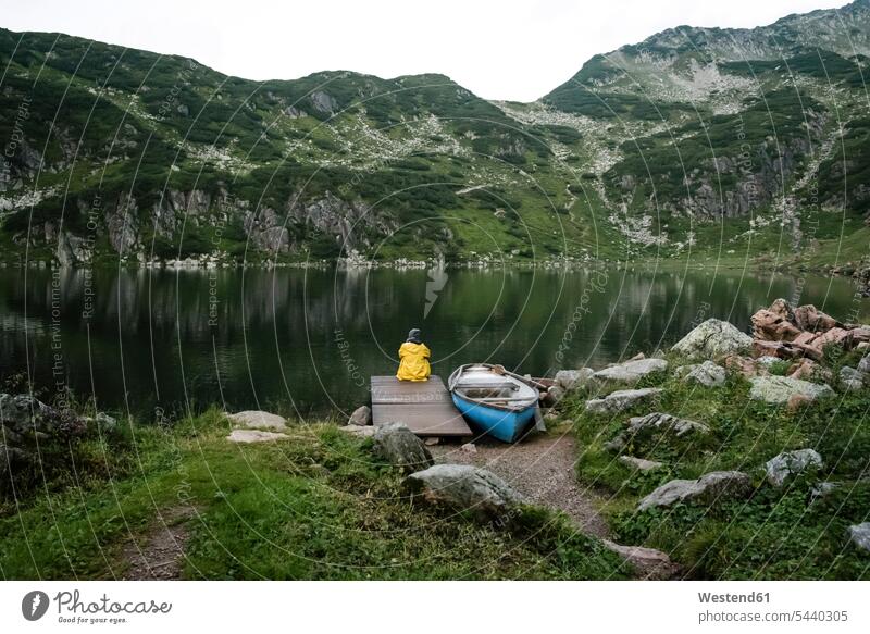 Österreich, Tirol, Fieberbrunn, Wildseeloder, Frau sitzt am Ufer des Wildsees neben einem Boot sitzen sitzend Boote weiblich Frauen See Seen Wasserfahrzeuge