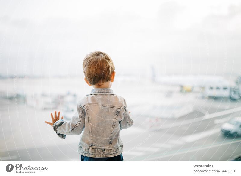 Spanien, Barcelona, Rückansicht eines kleinen Jungen, der durch ein Fenster auf dem Flughafen schaut Europäer Kaukasier kaukasisch Europäisch warten