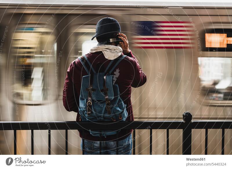 Junger Mann wartet am Bahnsteig auf die U-Bahn und trägt Kopfhörer Musik hören Kopfhoerer Metro U-Bahnhofsbahnsteig U-Bahnhöfe U-Bahnhoefe U-Bahnhofsbahnsteige