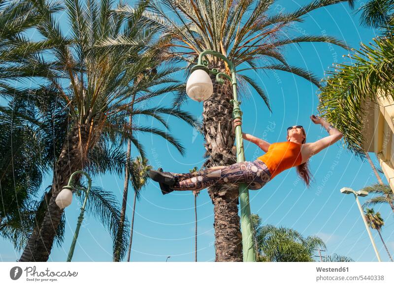 USA, Kalifornien, Los Angeles, Marina Del Rey, Sportliche Frau auf einem Laternenpfahl, Poledance Straßenlampe Straßenlampen Straßenlaterne Straßenlaternen
