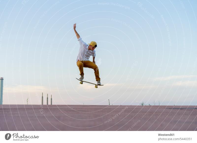 Junger Mann macht einen Skateboard-Trick auf einer Fahrbahn in der Dämmerung Abenddämmerung stimmungsvoll Stimmung Abendstimmung Abenddaemmerung Skateboarder