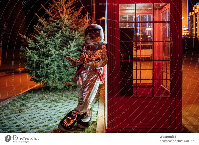 Spaceman lehnt gegen eine Telefonzelle in der Nacht lesen Telefonbuch Astronaut Astronauten anlehnen angelehnt lehnend Telefonzellen Telefonhaeuschen