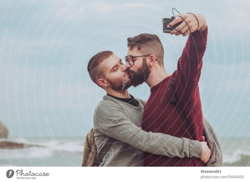 Homosexuelles Paar nimmt Selfie beim Küssen vor dem Meer Selfies Pärchen Paare Partnerschaft küssen Kuss Mensch Menschen Leute People Personen Homosexualität