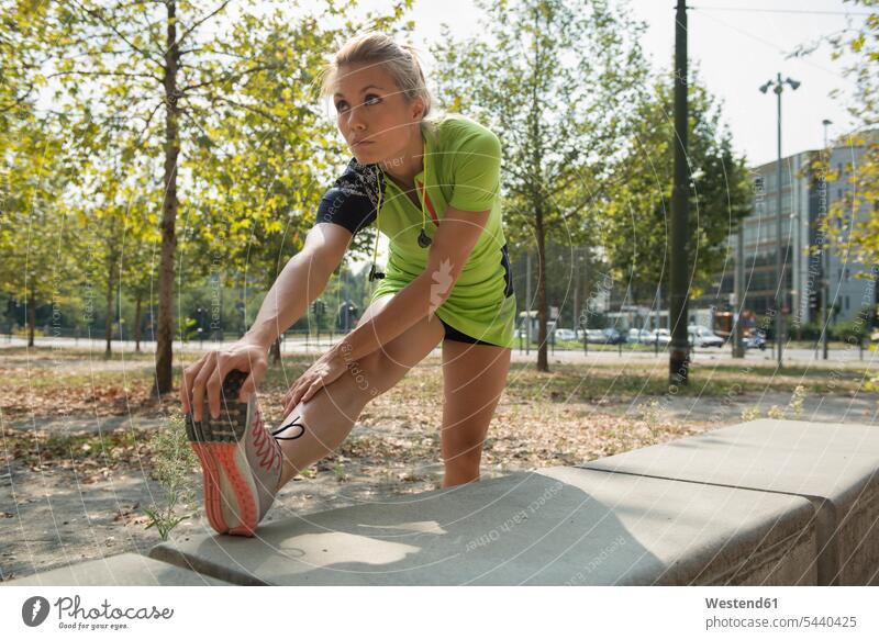 Weibliche Athletin beim Stretching im Stadtpark Park Parkanlagen Parks Frau weiblich Frauen trainieren Joggerin Joggerinnen Sportlerin Sportlerinnen dehnen