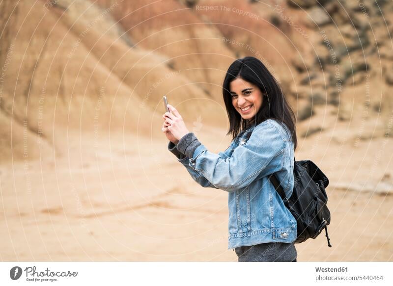 Spanien, Navarra, Bardenas Reales, lachende junge Frau im Naturpark, die ein Selfie mit ihrem Handy macht weiblich Frauen Smartphone iPhone Smartphones