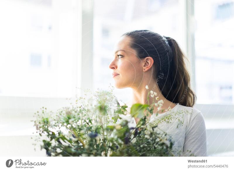 Frau mit Blumen, die aus dem Fenster schaut Blüte weiblich Frauen wegsehen Blick zur Seite wegschauen Pflanze Pflanzenwelt Flora Erwachsener erwachsen Mensch
