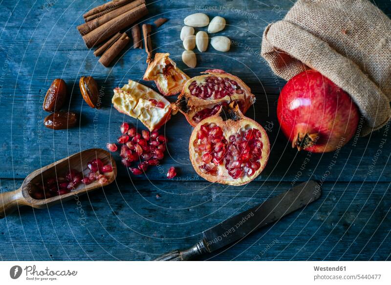 Granatapfel in Scheiben und ganz, Granatapfelkerne, Datteln, Mandeln und Zimtstangen auf Holz Niemand Frische frisch Anordnung Positionierung Anordnungen