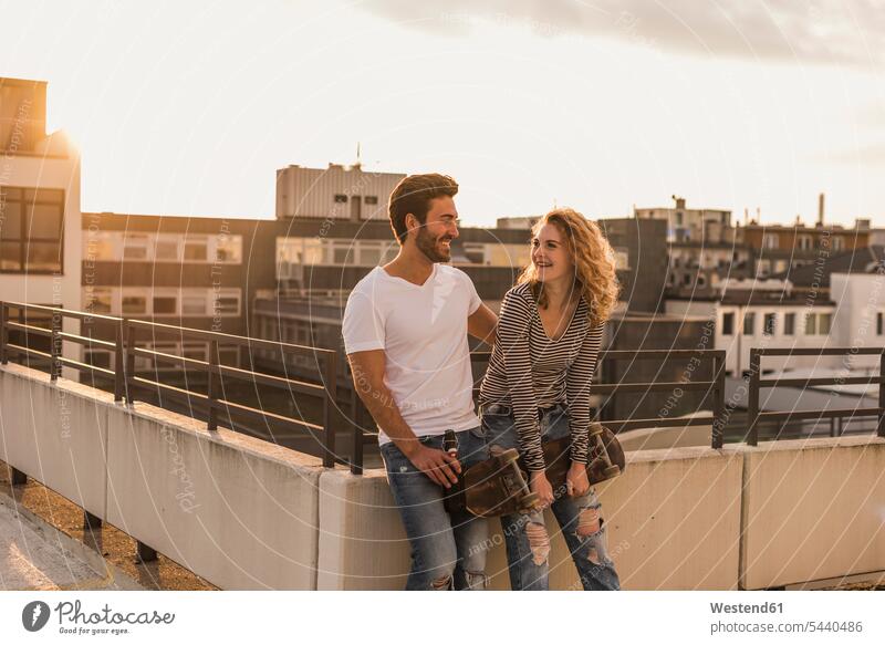 Glückliches junges Paar entspannt sich bei Sonnenuntergang auf der Dachterrasse Dachterrassen Sonnenuntergänge glücklich glücklich sein glücklichsein Pärchen