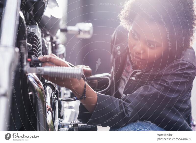 Junge Frau, die ihr Motorrad wartet weiblich Frauen Motorräder Erwachsener erwachsen Mensch Menschen Leute People Personen Kraftfahrzeug Verkehrsmittel KFZ