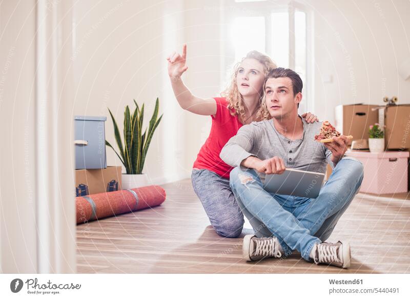 Junges Paar in neuer Wohnung sitzt mit Tablette auf dem Boden Pärchen Paare Partnerschaft wohnen Wohnungen Mensch Menschen Leute People Personen Wohnen Umzug