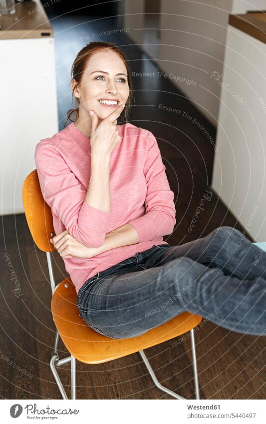 Porträt einer lächelnden jungen Frau, die zu Hause auf einem Holzstuhl sitzt Zuhause daheim sitzen sitzend Stuhl Stuehle Stühle weiblich Frauen Portrait