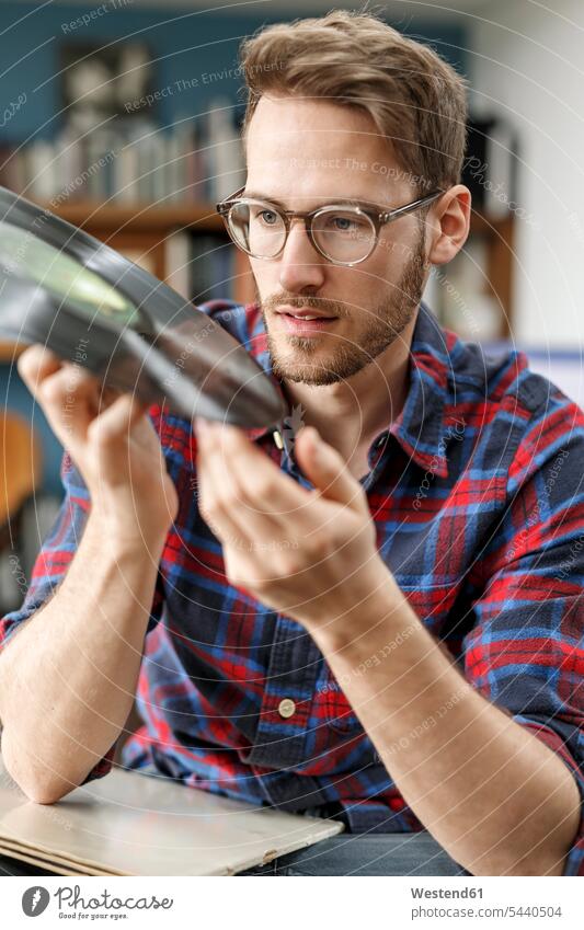 Junger Mann zu Hause mit Vinyl-Schallplatte in der Hand Zuhause daheim halten Männer männlich Schallplatten Erwachsener erwachsen Mensch Menschen Leute People