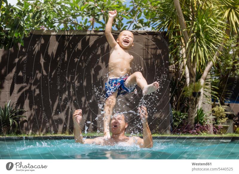 Vater und Sohn amüsieren sich im Schwimmbad Papas Väter Vati Vatis Papis Söhne Spaß Spass Späße spassig Spässe spaßig Swimmingpool Swimmingpools Schwimmbecken