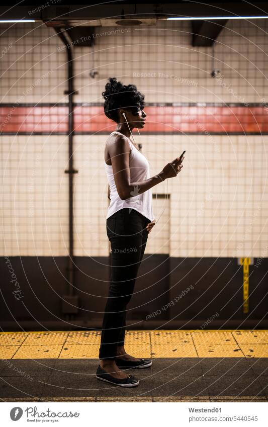 USA, New York City, Manhattan, Frau wartet am Bahnsteig der U-Bahn-Station weiblich Frauen warten U-Bahnhofsbahnsteig U-Bahnhöfe U-Bahnhoefe