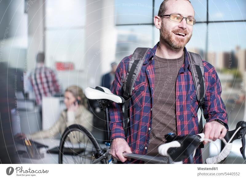 Lässiger Mann mit Fahrrad im modernen Büro Männer männlich Office Büros tragen transportieren Bikes Fahrräder Räder Rad Erwachsener erwachsen Mensch Menschen
