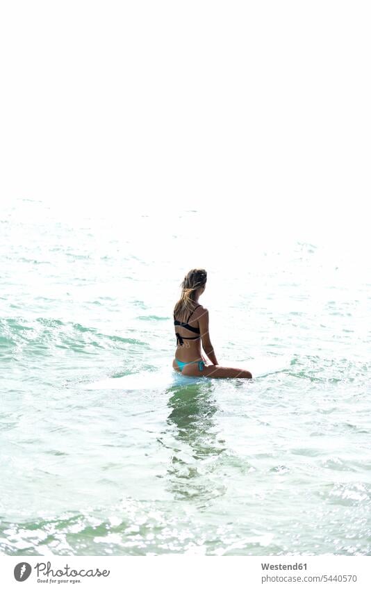 Frau sitzt auf einem Surfbrett im Meer Surfbretter surfboard surfboards Surfen Surfing Wellenreiten weiblich Frauen Meere Wassersport Sport Erwachsener