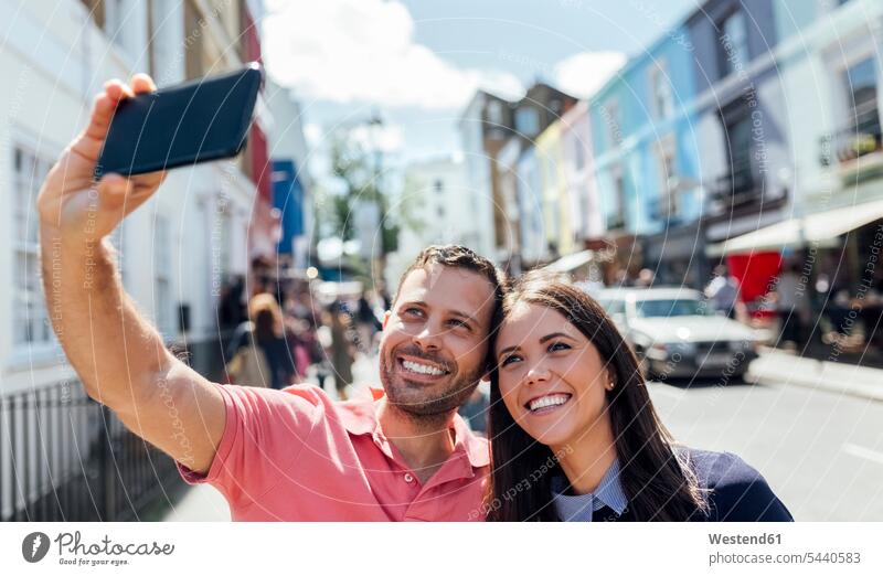 UK, London, Portobello Road, glückliches Paar macht Selfie mit Handy Pärchen Paare Partnerschaft Selfies Mensch Menschen Leute People Personen Smartphone iPhone