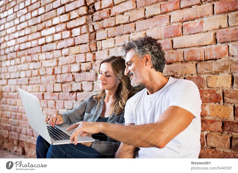 Geschäftsmann und -frau sitzen in einem Loft, benutzen einen Laptop und gründen ein Start-up-Unternehmen sitzend sitzt Unternehmensgründung Existenzgründung