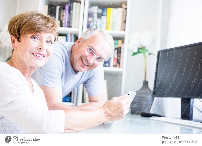 Älteres Ehepaar am Schreibtisch mit digitalem Tablett lächeln Paar Pärchen Paare Partnerschaft Tablet Computer Tablet-PC Tablet PC iPad Tablet-Computer Mensch