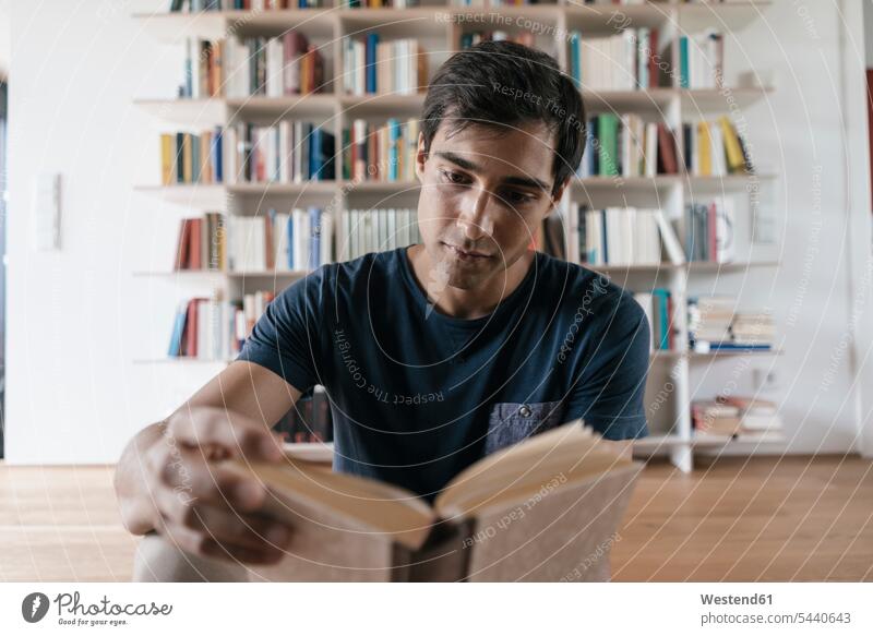 Junger Mann liest zu Hause Buch lesen Lektüre Bücher Männer männlich Erwachsener erwachsen Mensch Menschen Leute People Personen Deutschland Freizeit Muße