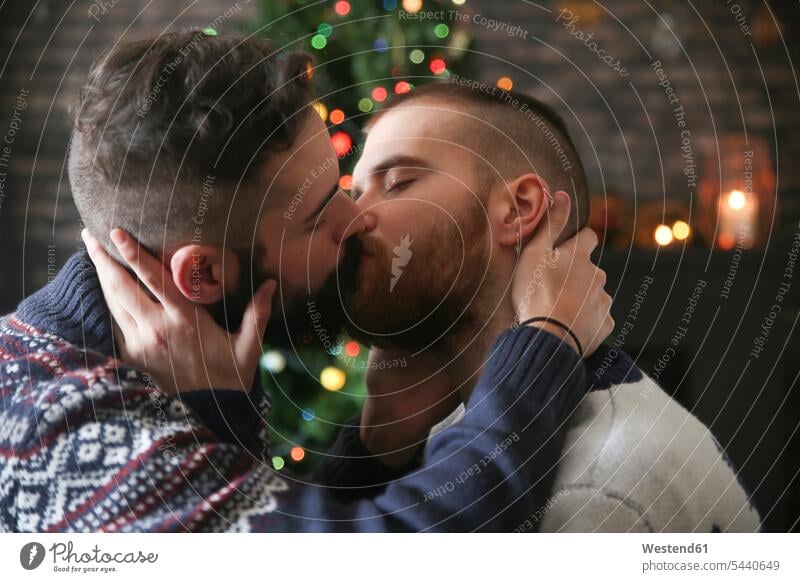 Homosexuelles Paar zur Weihnachtszeit zu Hause küssen Schwules Paar Schwuler Weihnachten Christmas X-Mas X mas Küsse Kuss Gleichgeschlechtliches Paar
