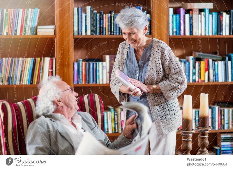 Älterer Mann und Frau sitzen in der Bibliothek und lesen Buch und Zeitung Altersheim Altenheim Seniorenheim Seniorin älter Seniorinnen alt Sessel ältere Männer