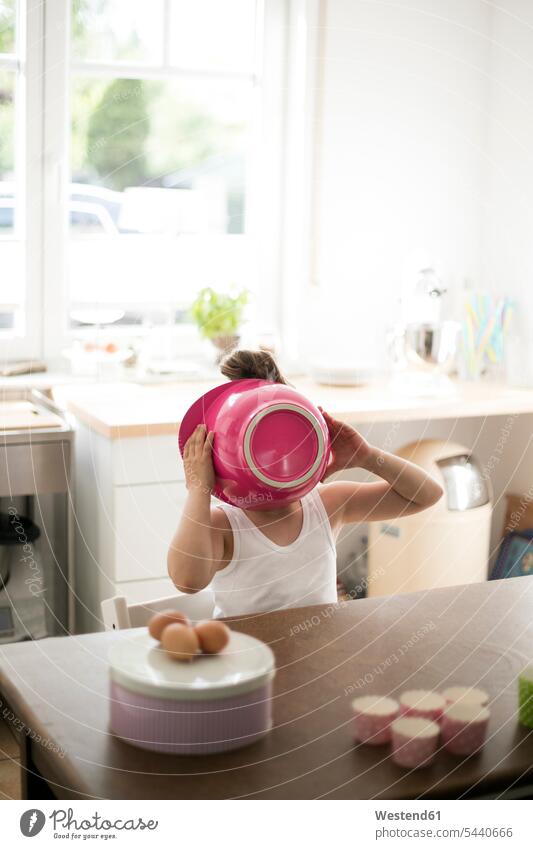 Kleines Mädchen in der Küche bedeckt ihr Gesicht mit rosa Rührschüssel Schüssel Schalen Schälchen Schüsseln weiblich verstecken backen Kind Kinder Kids Mensch