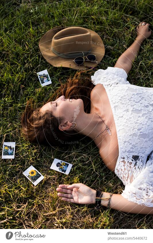 Glückliche Frau liegt auf einem Feld, umgeben von Sofortbildern Wiese Wiesen Foto Fotos Felder liegen liegend weiblich Frauen glücklich glücklich sein