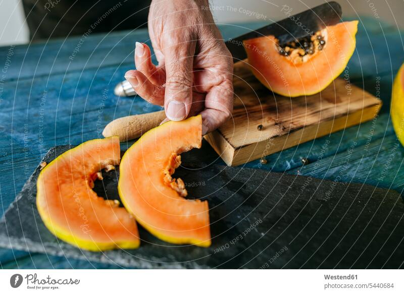 Nahaufnahme von Männerhänden, die Papayastücke auf eine Schieferplatte legen schneiden Frische frisch Hälfte halbe halbiert halber Haelfte Mann männlich