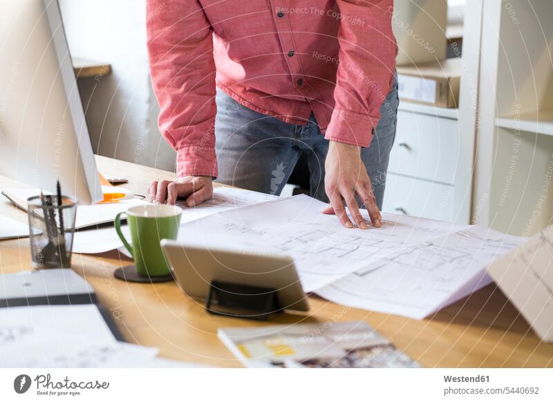 Nahaufnahme eines Mannes, der am Schreibtisch im Büro an einer Blaupause arbeitet Office Büros Arbeitsplatz Arbeitsstätte Arbeitstelle Bauplan Architekturplan