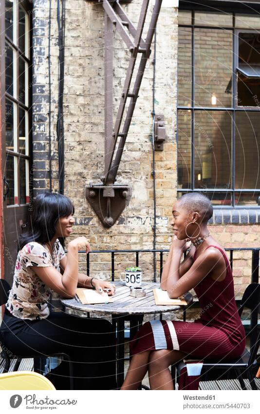 Zwei Freunde unterhalten sich in einem Restaurant Freundinnen Freundschaft Kameradschaft sitzen sitzend sitzt sprechen reden Lokal Speiserestaurant Lokale
