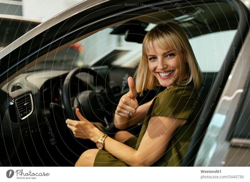 Blonde Frau wählt neues Auto im Autohaus Kundin Wagen PKWs Automobil Autos aussuchen auswählen Autohäuser Autohaeuser Autohandlung Autohandlungen kaufen Kauf