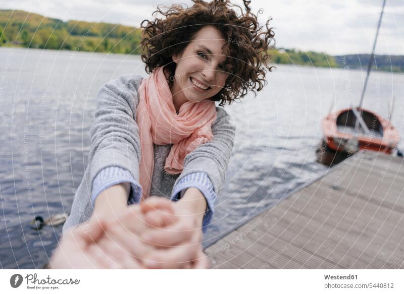 Frau steht auf Steg und zieht an der Hand des Mannes Freizeit Muße Hände Stege Anlegestelle Boot Boote ziehen weiblich Frauen See Seen Mensch Menschen Leute