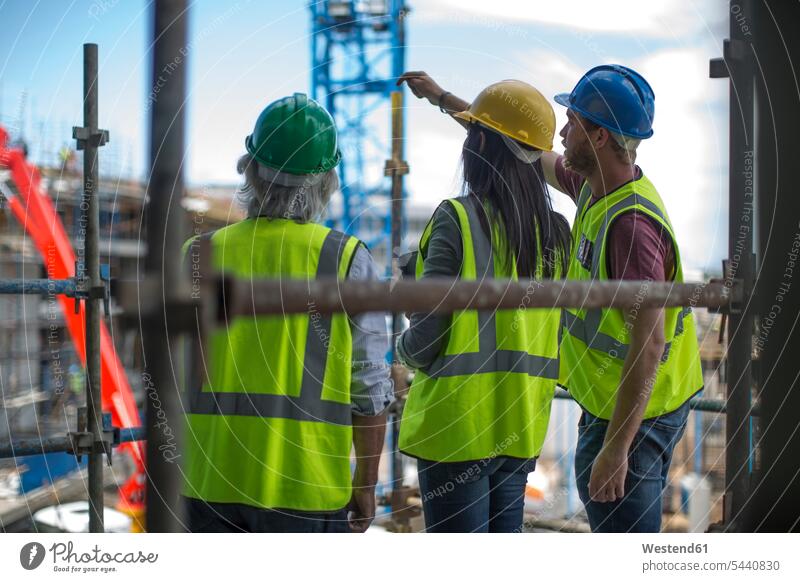 Bauarbeiter im Gespräch mit Mann und Frau auf einer Baustelle arbeiten Arbeit Baustellen sprechen reden Handwerker Handwerksberuf Handwerksberufe Gewerbe
