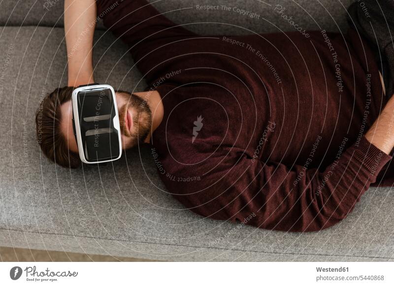 Auf der Couch liegender Mann mit Virtual-Reality-Brille Virtual Reality Brille Virtual Reality-Brille VR Brille Männer männlich Wearable Wearables